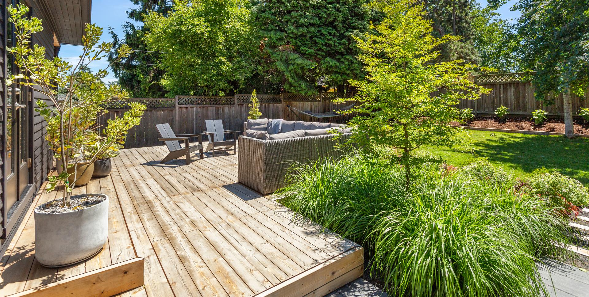 Backyard deck with furniture, lawn, treees, and plantings at a private residence in Portland.