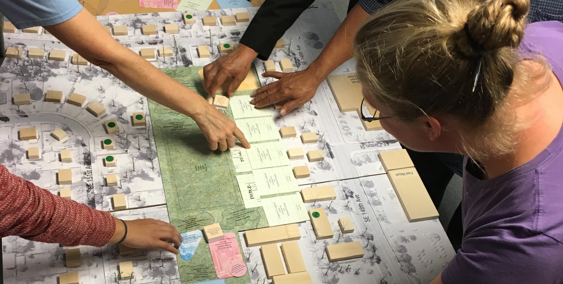 Community members collaborating over a site plan during a design workshop.